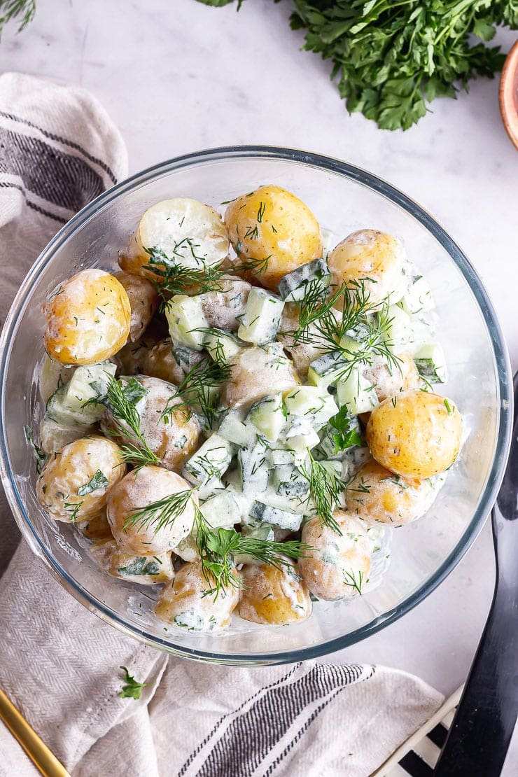 Overhead shot of healthy potato salad with herbs on a marble background