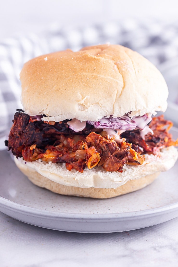 Side on shot of pulled jackfruit sandwich on a grey plate