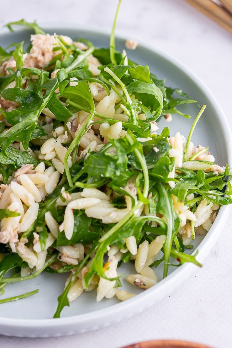 Close up of orzo pasta salad with salmon and rocket on a marble background