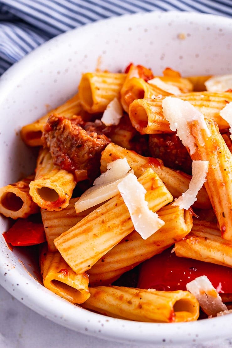 Close up of sausage pasta with parmesan in a white bowl