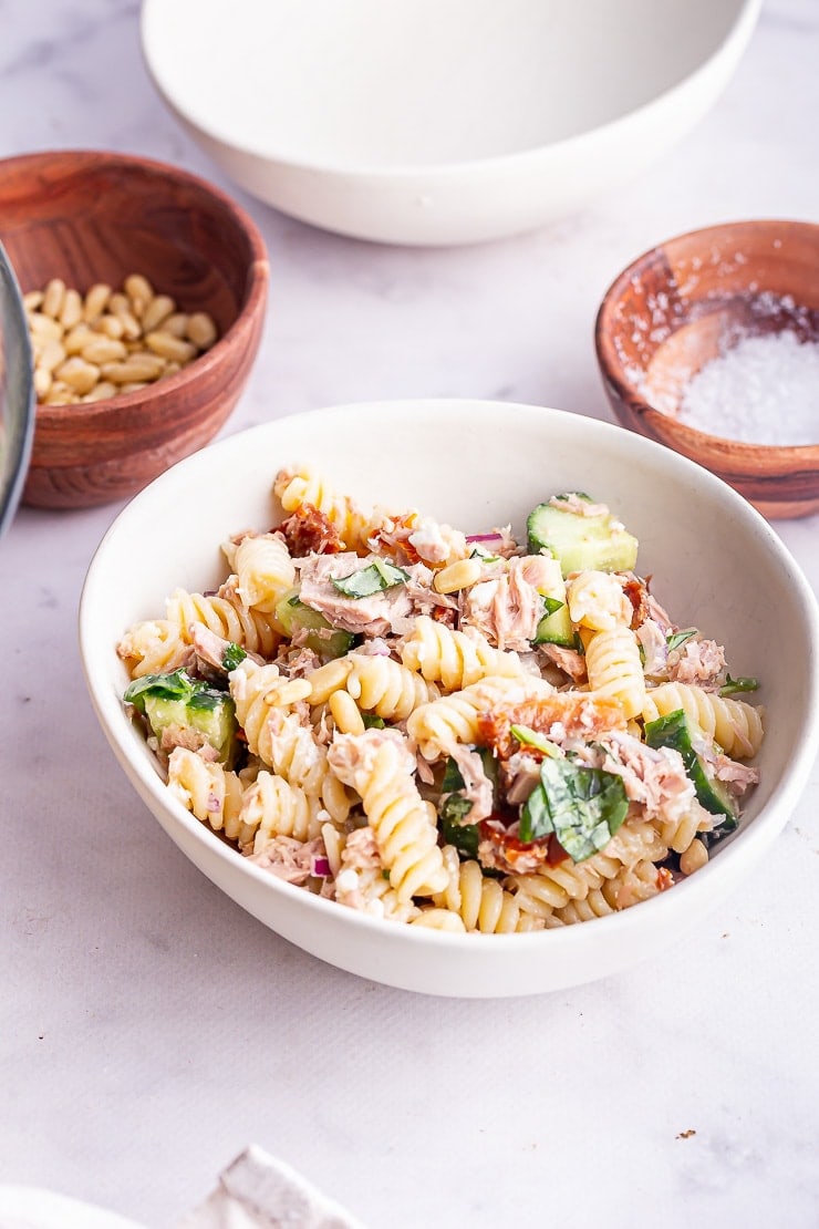 White bowl of tuna pasta salad on a marble surface