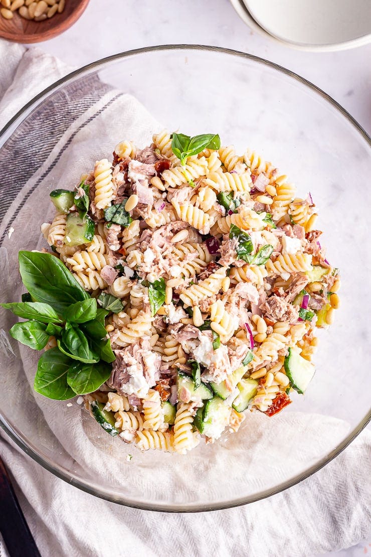 Overhead shot of tuna pasta salad in a glass bowl with basil