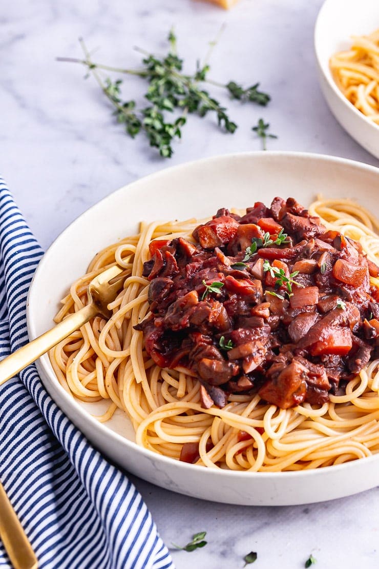 Mushroom bolognese with spaghetti on a white bowl with a striped cloth