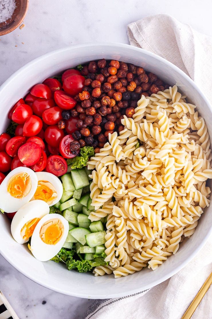 Overhead shot of cobb salad with pasta in a grey bowl on a marble background