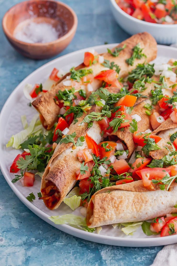 Grey plate of chicken wraps with salsa on a blue background