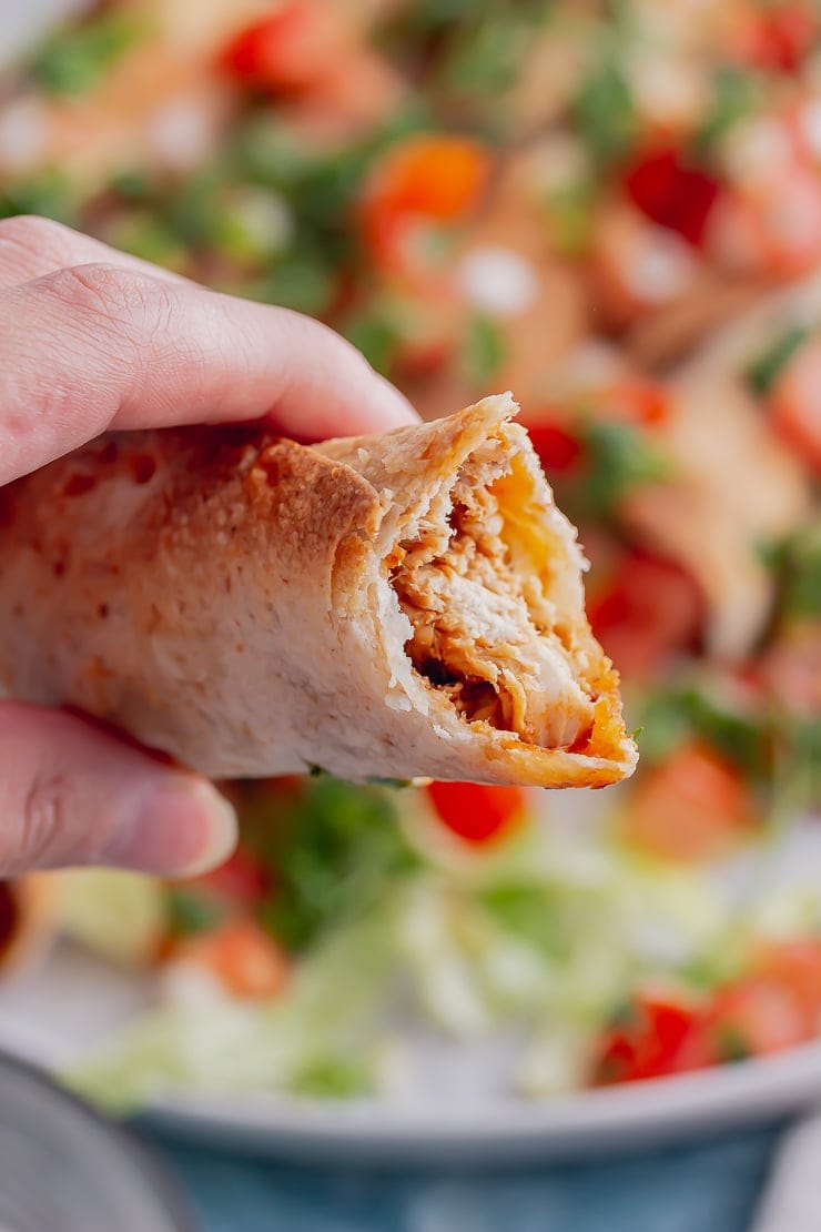 Close up of a chicken taquito with a bite taken