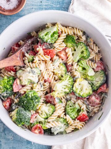 Pasta with summer vegetables and creamy vegan dressing with a wooden spoon