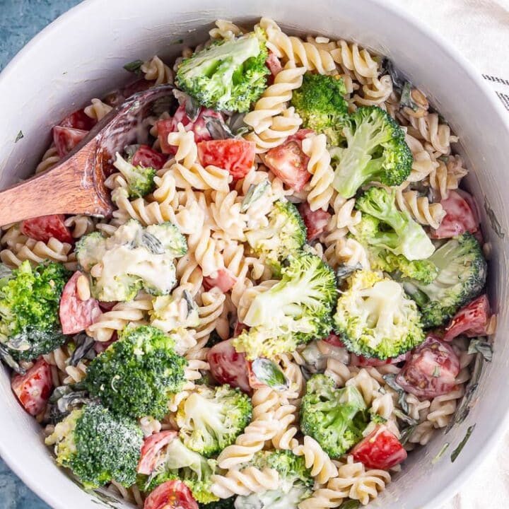 Pasta with summer vegetables and creamy vegan dressing with a wooden spoon