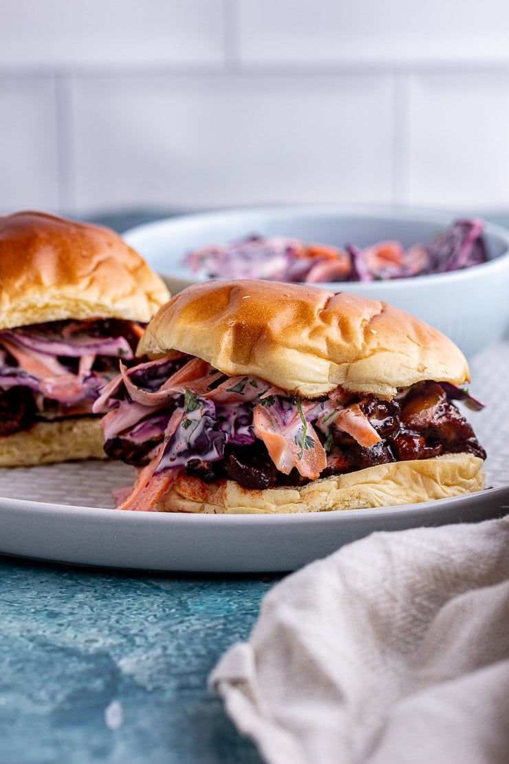 Side on shot of vegetarian pulled pork sandwich with slaw on a blue background