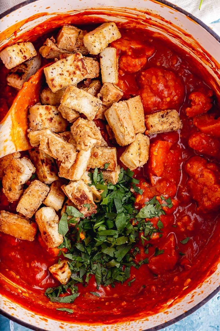 Close up of crispy tofu in a red curry sauce