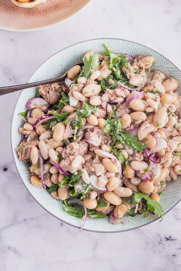 Overhead shot of blue bowl of salad with a spoon