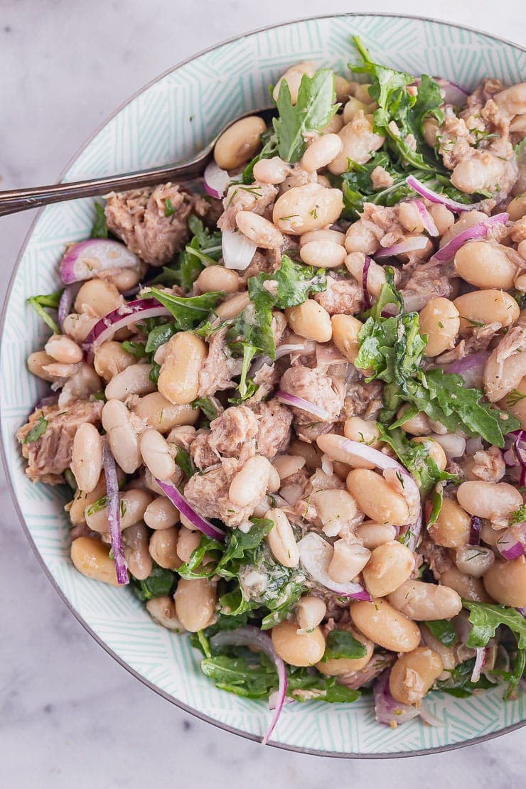 Overhead close up of tuna fish salad in a blue bowl with a spoon