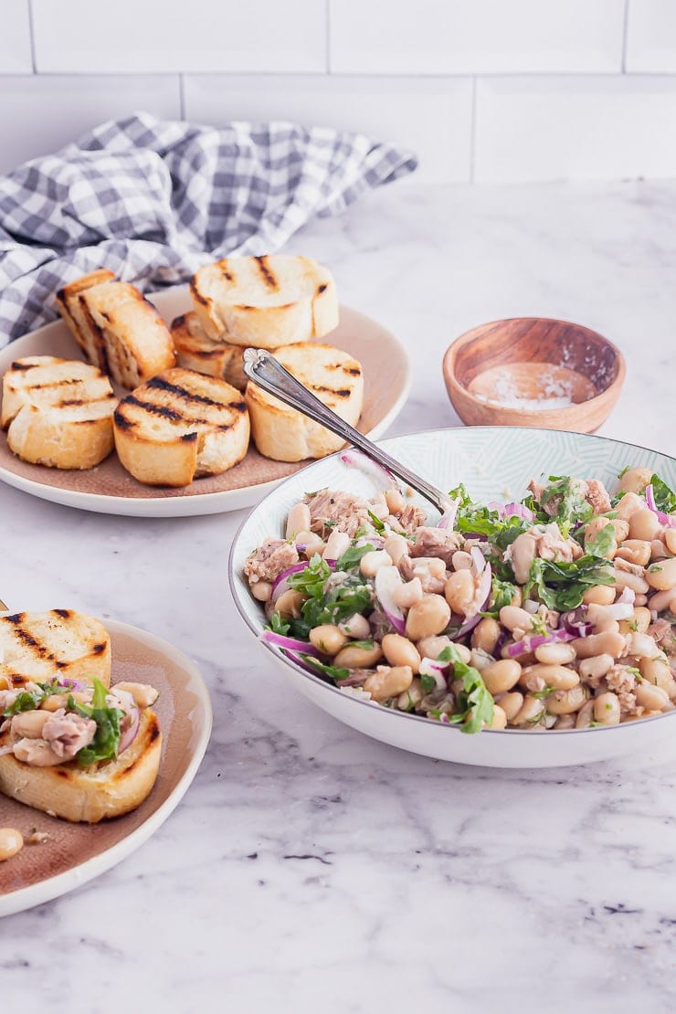 Bowl of food with a spoon and toasts on a marble background