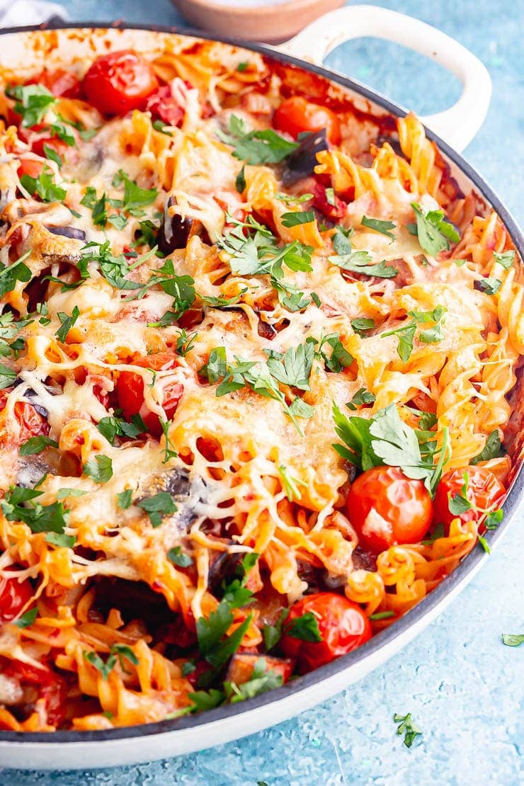 White dish of aubergine pasta bake on a blue background