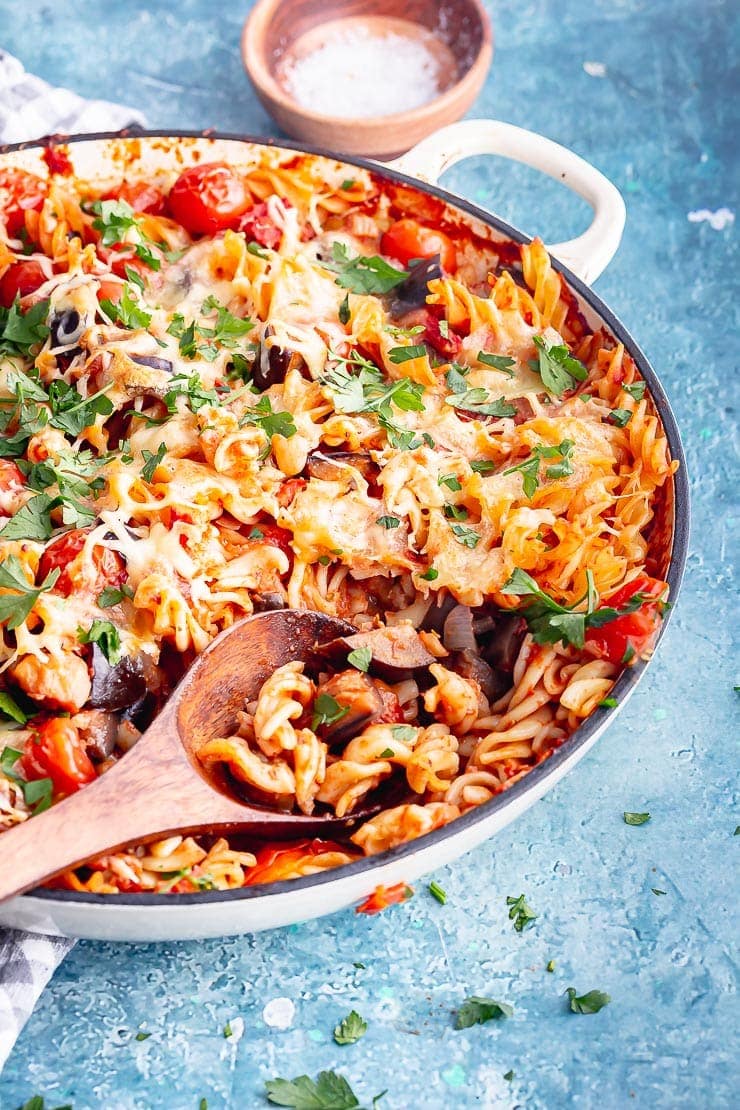 Wooden spoon in a dish of eggplant pasta with mozzarella