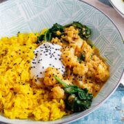 Lentil cauliflower curry with yoghurt and spinach on a blue background