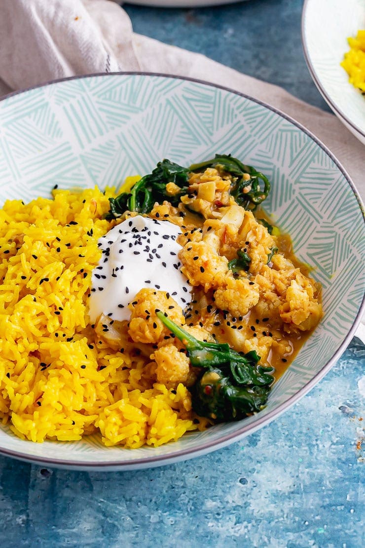Lentil cauliflower curry with yoghurt and spinach on a blue background