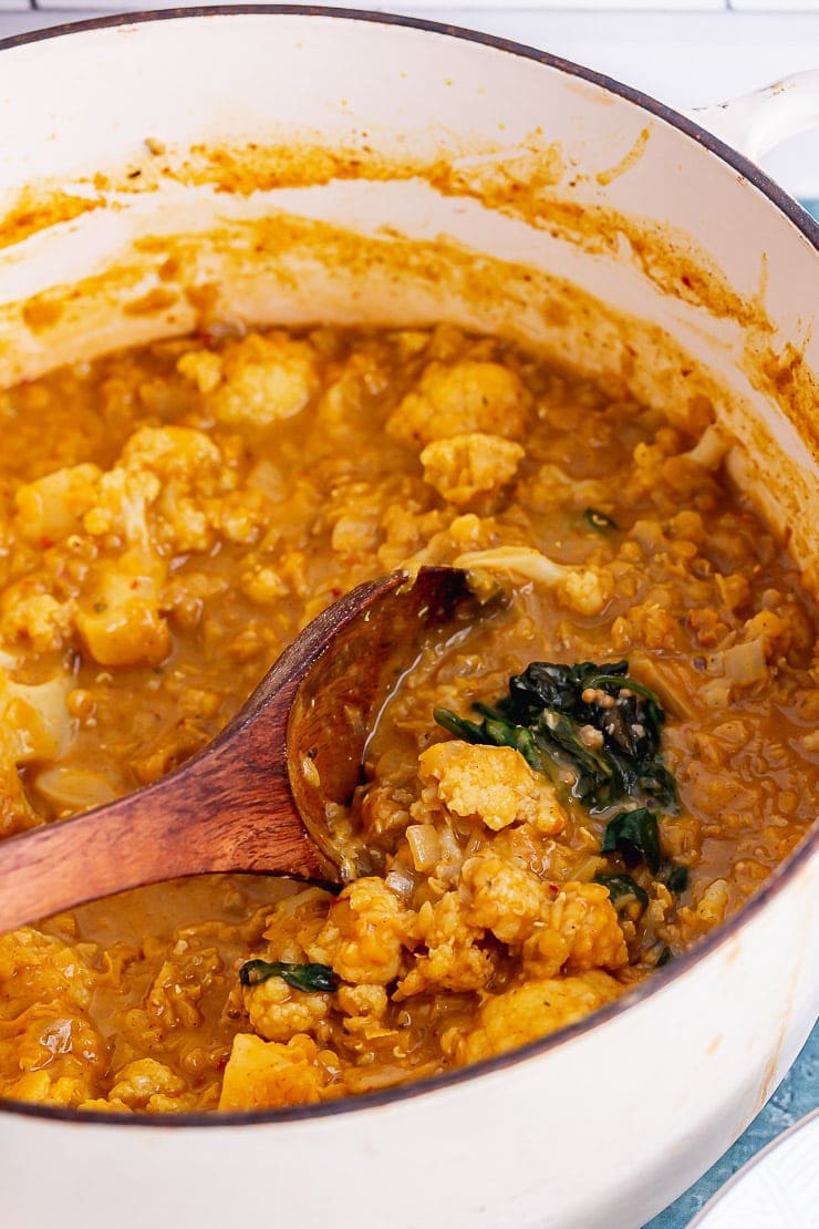 Cauliflower dal with a wooden spoon in a white casserole dish