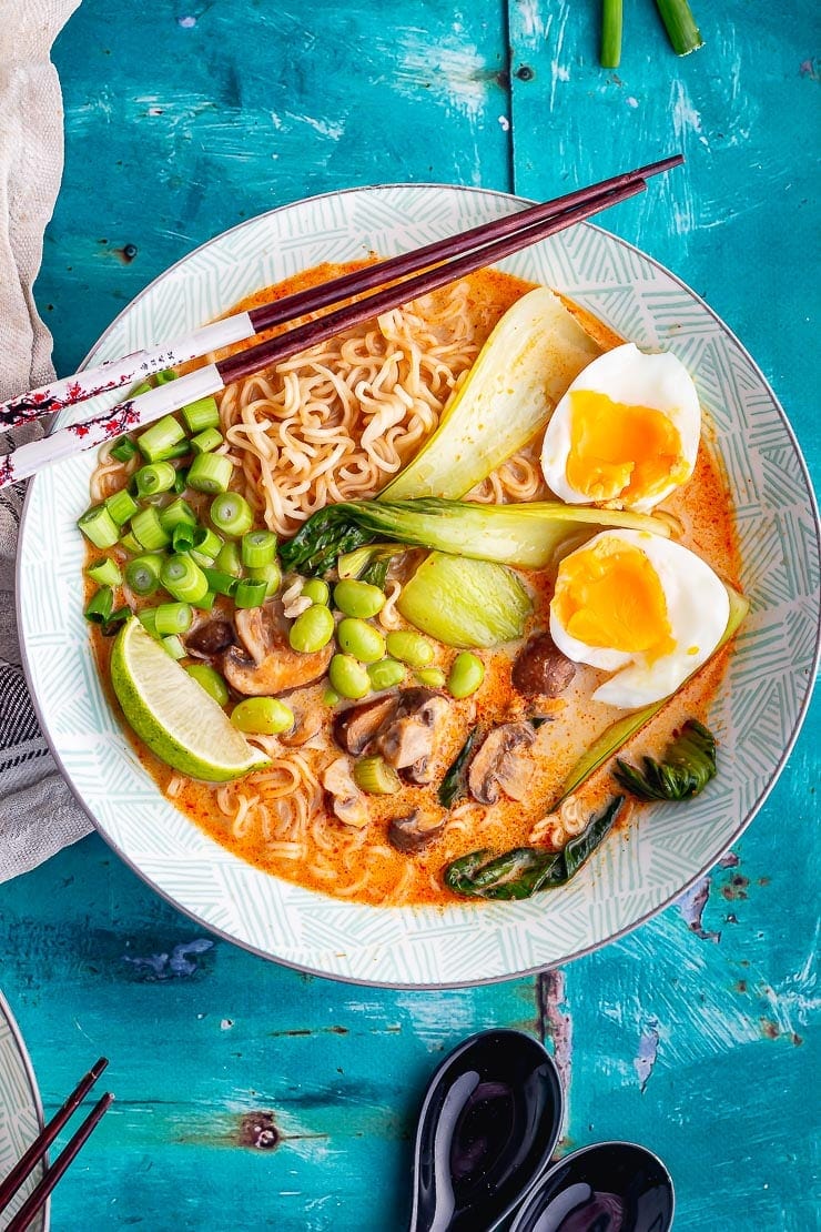 Overhead shot of coconut curry ramen with chopsticks in a blue bowl