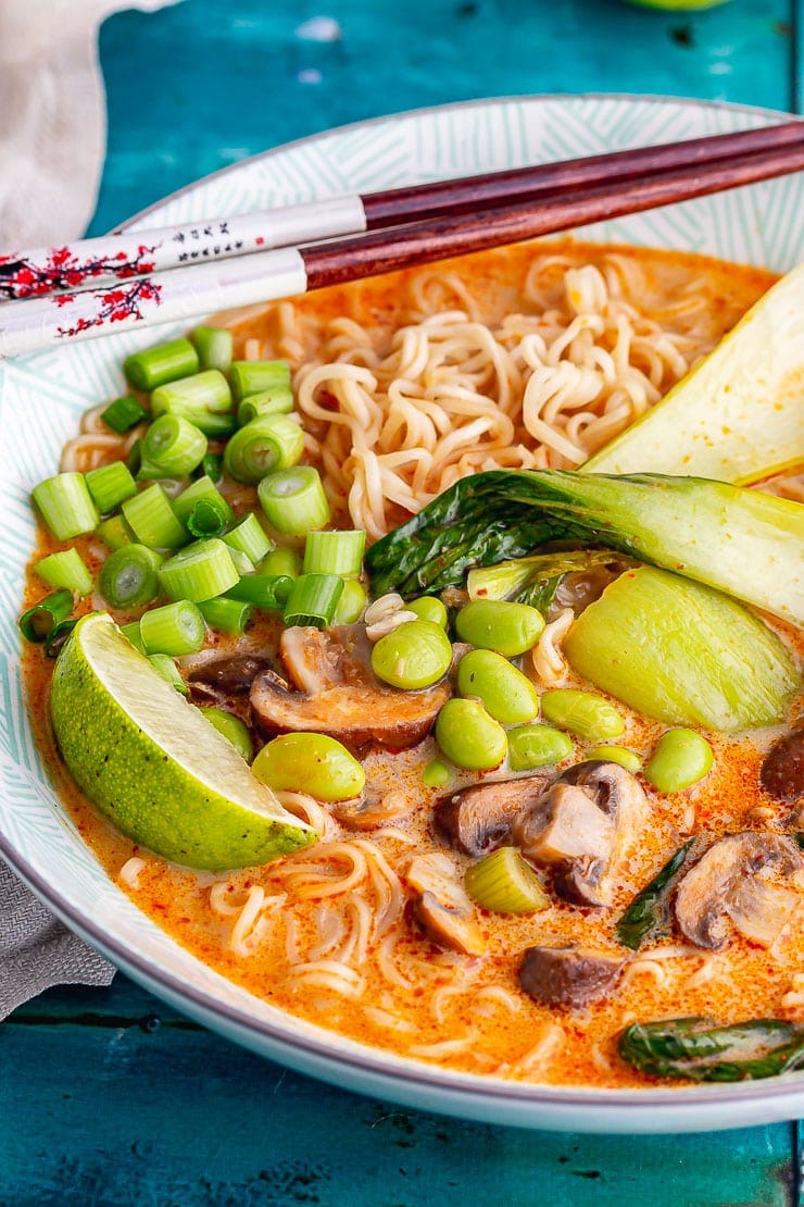 Bowl of noodle soup with lime and edamame and chopsticks