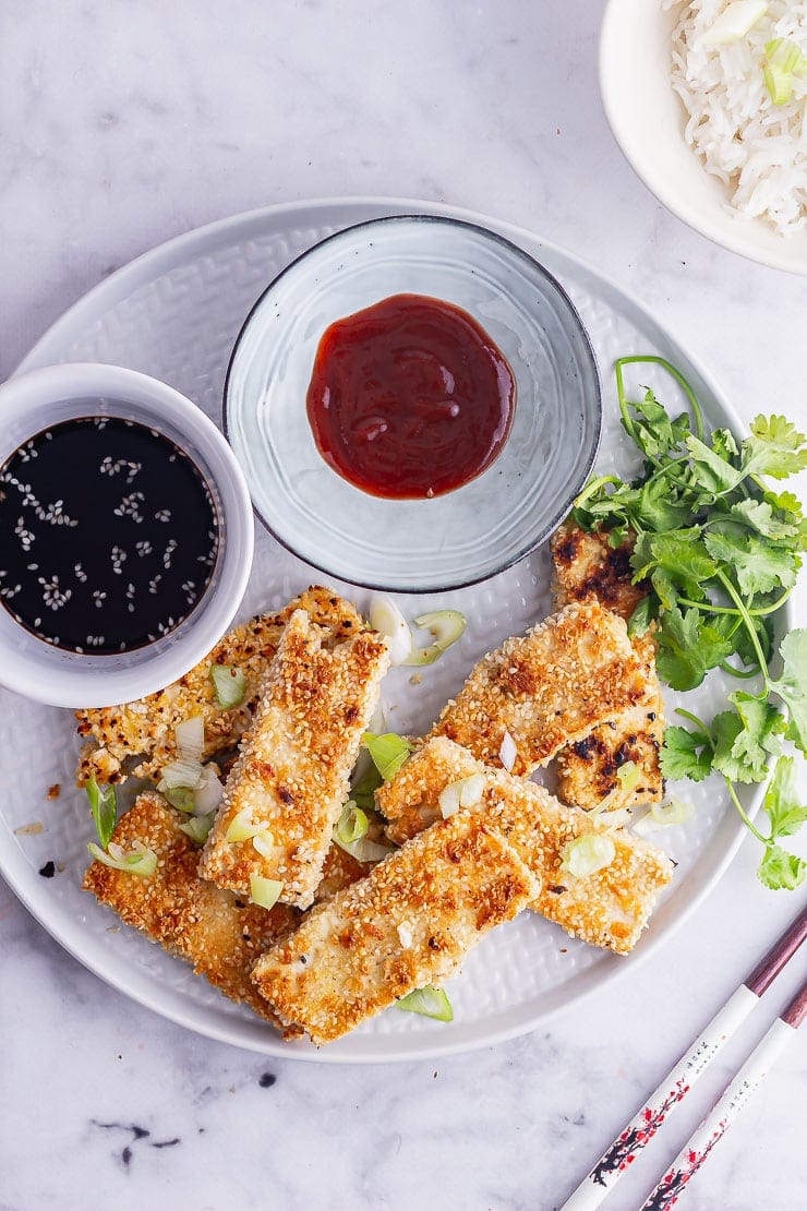 Overhead shot of sesame crusted tofu with soy sauce and hot sauce