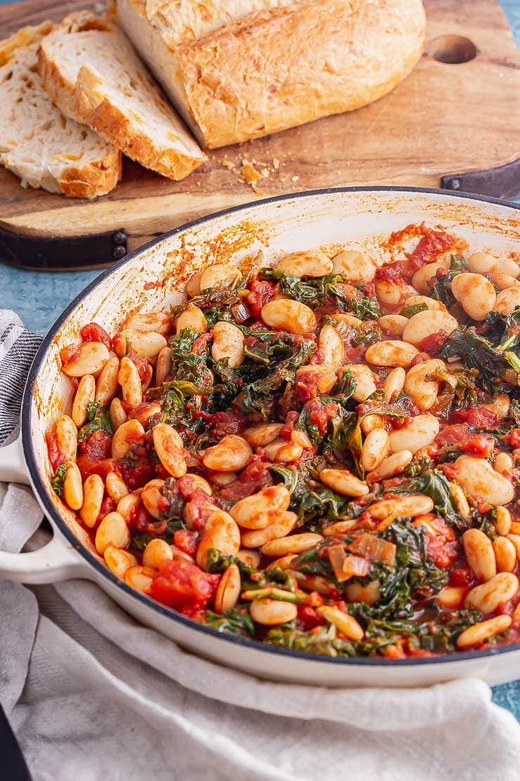 White dish of bean stew with bread in the background