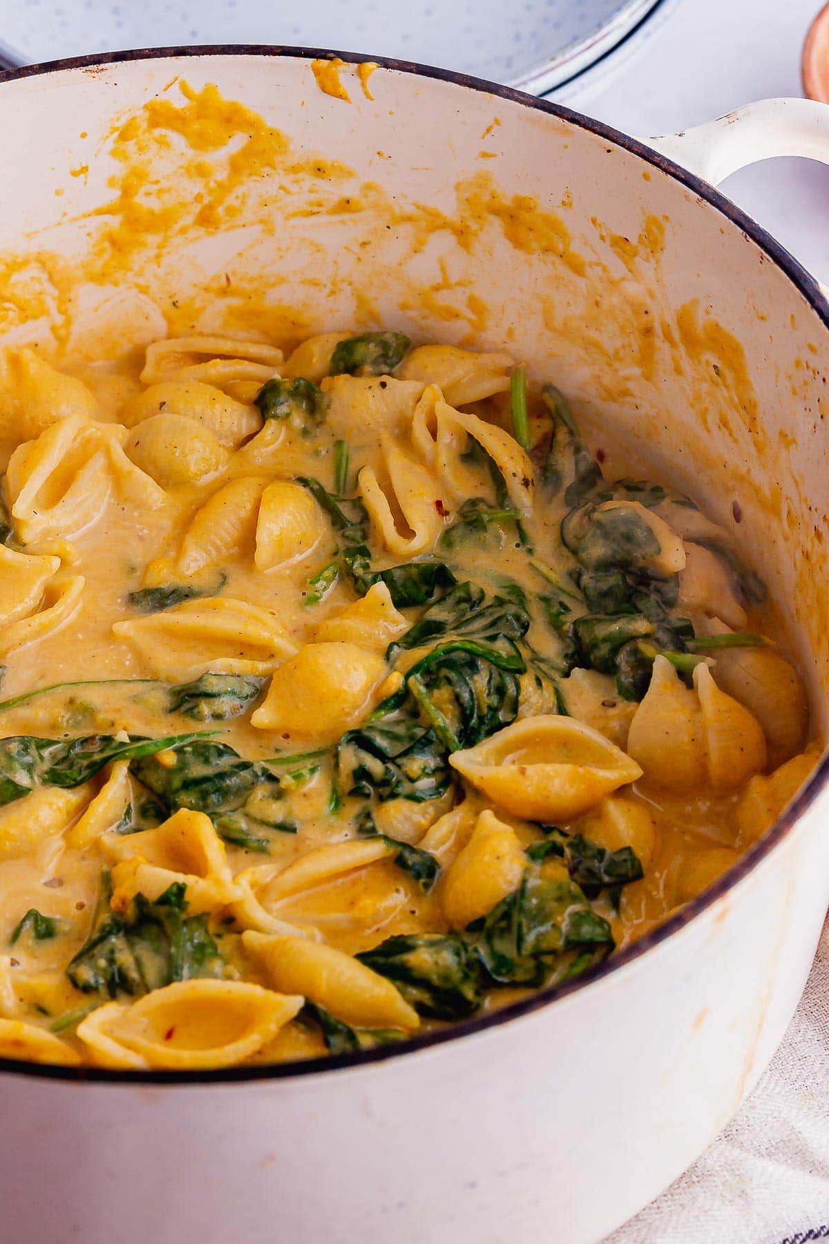 Creamy butternut squash pasta with spinach in a white pot