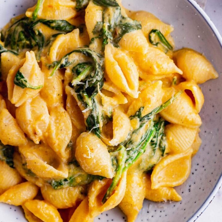 Overhead shot of butternut squash pasta sauce with spinach in a blue bowl