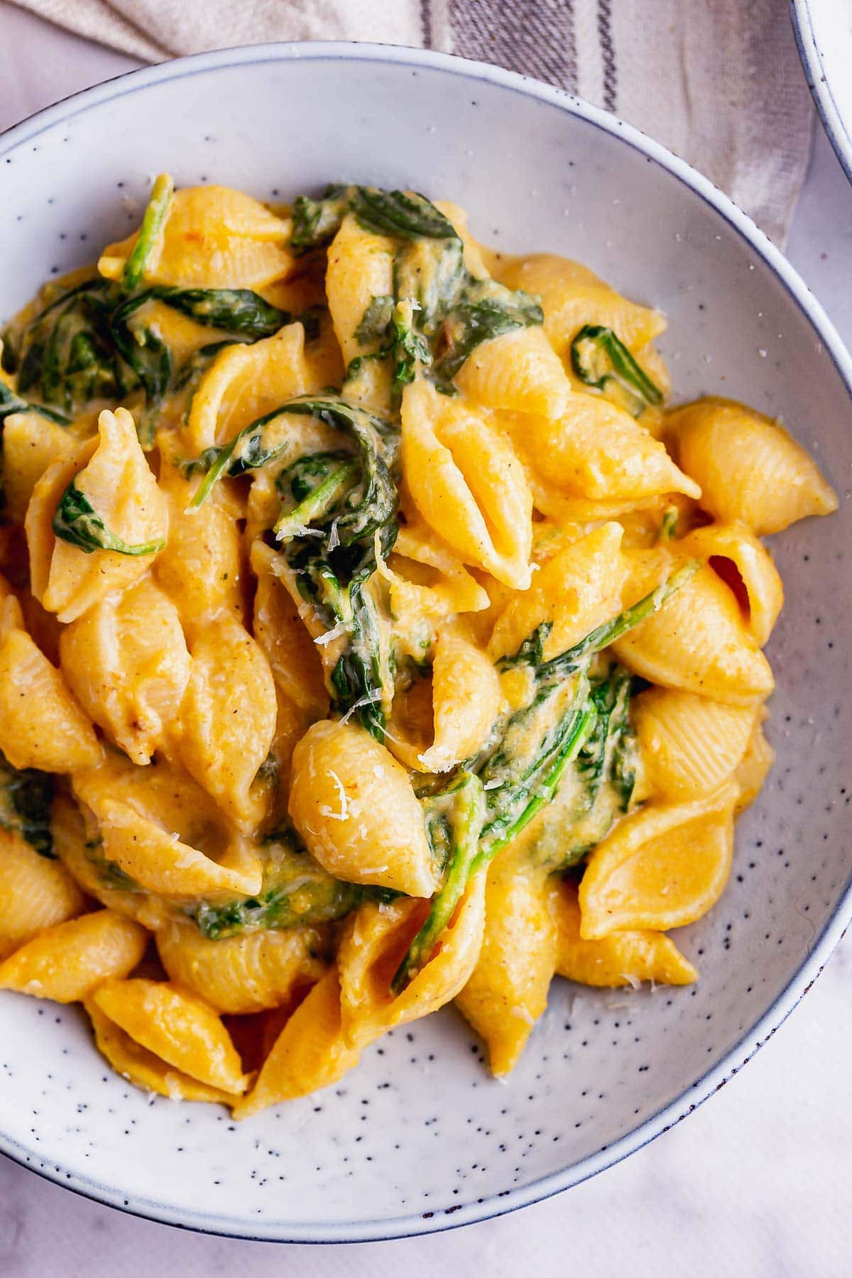 Overhead shot of butternut squash pasta sauce with spinach in a blue bowl