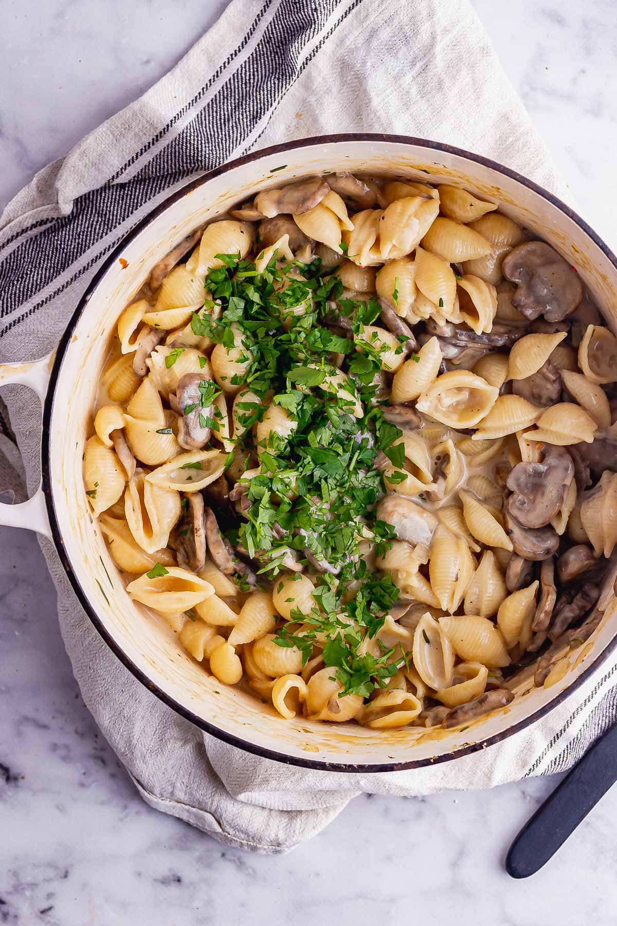 Overhead shot of creamy mushroom stroganoff on a cream cloth over a marble surface