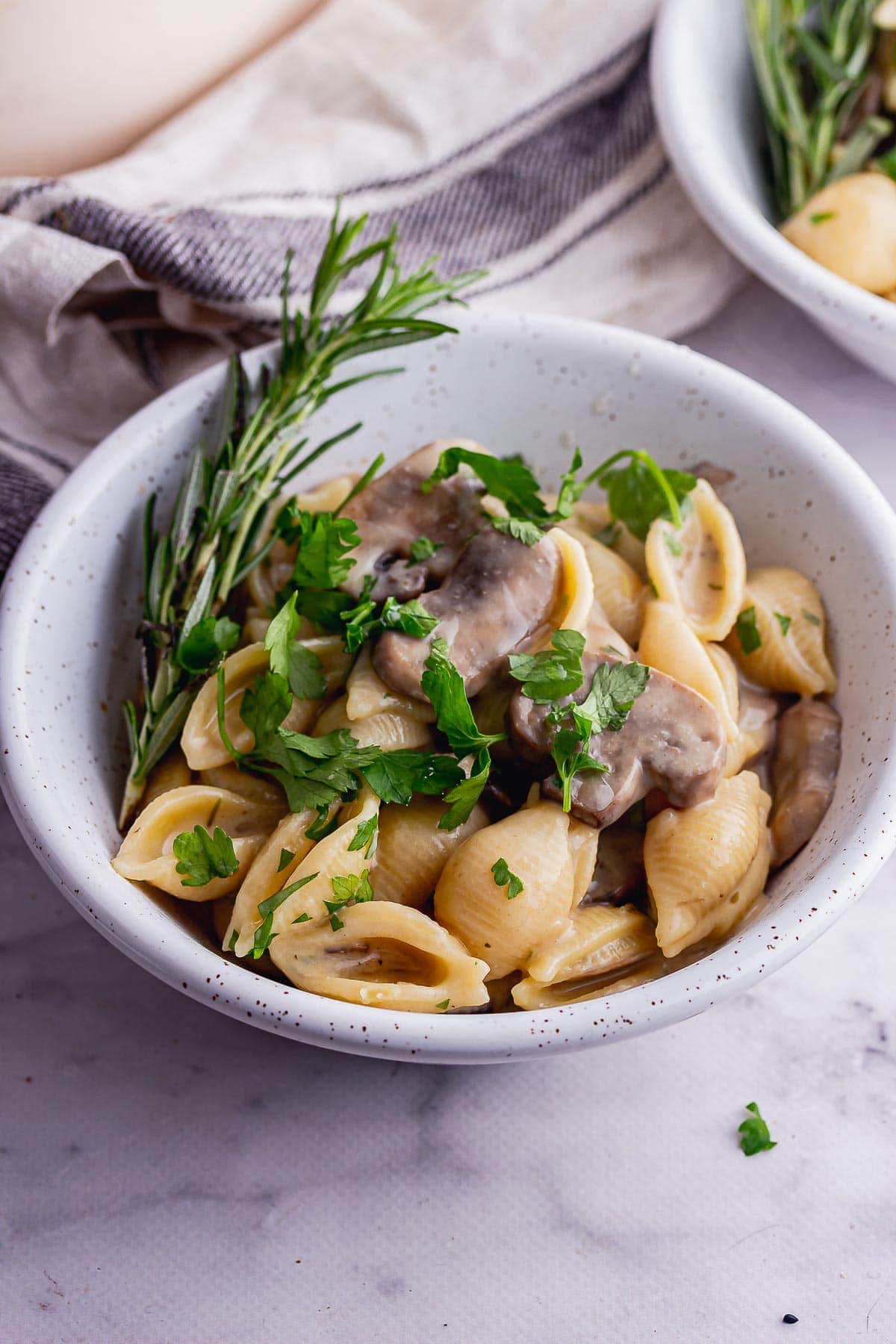 Grey bowl of creamy pasta with mushrooms on a marble background
