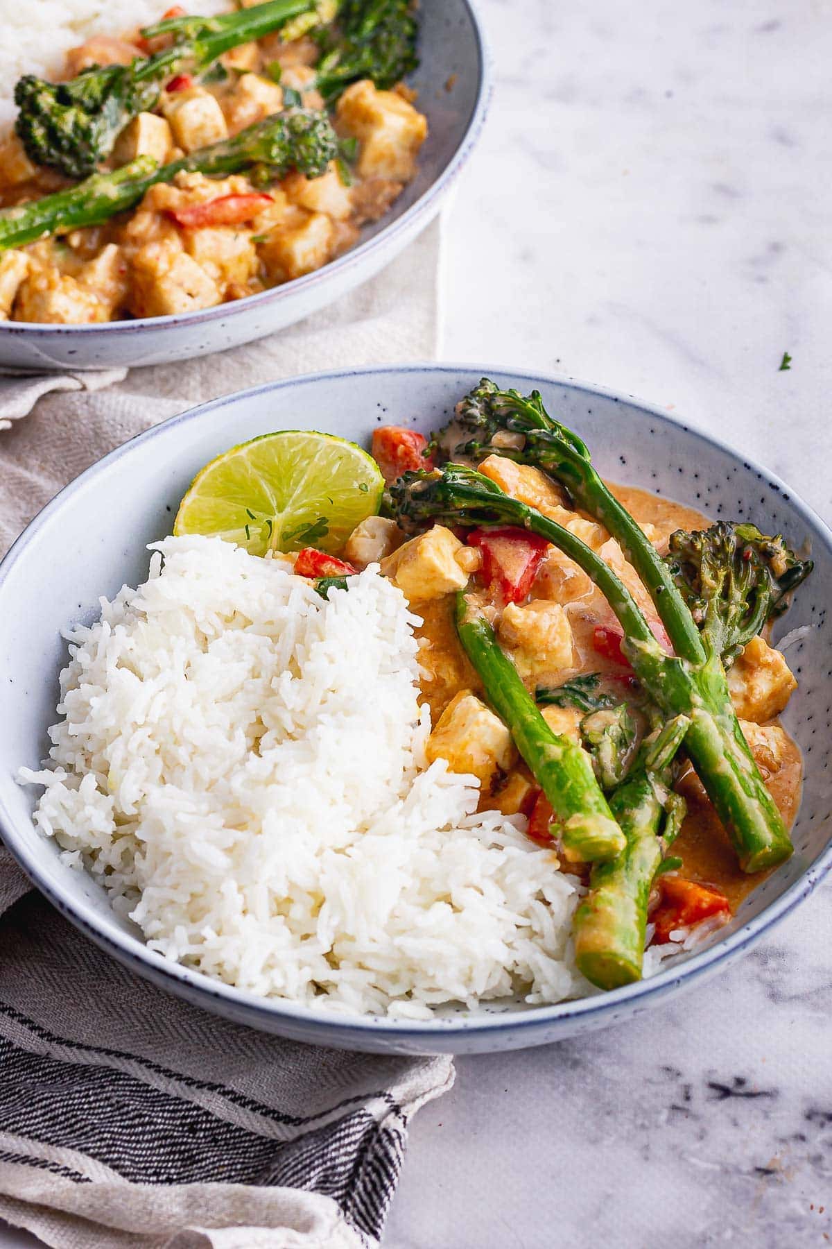 Blue bowl of veggie curry with peanut sauce and rice