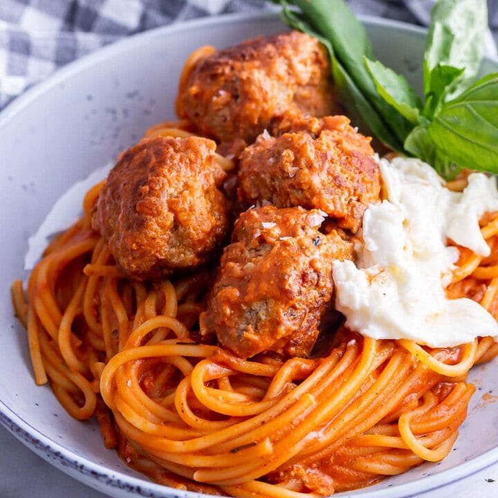 Close up of meatballs and spaghetti with mozzarella and basil