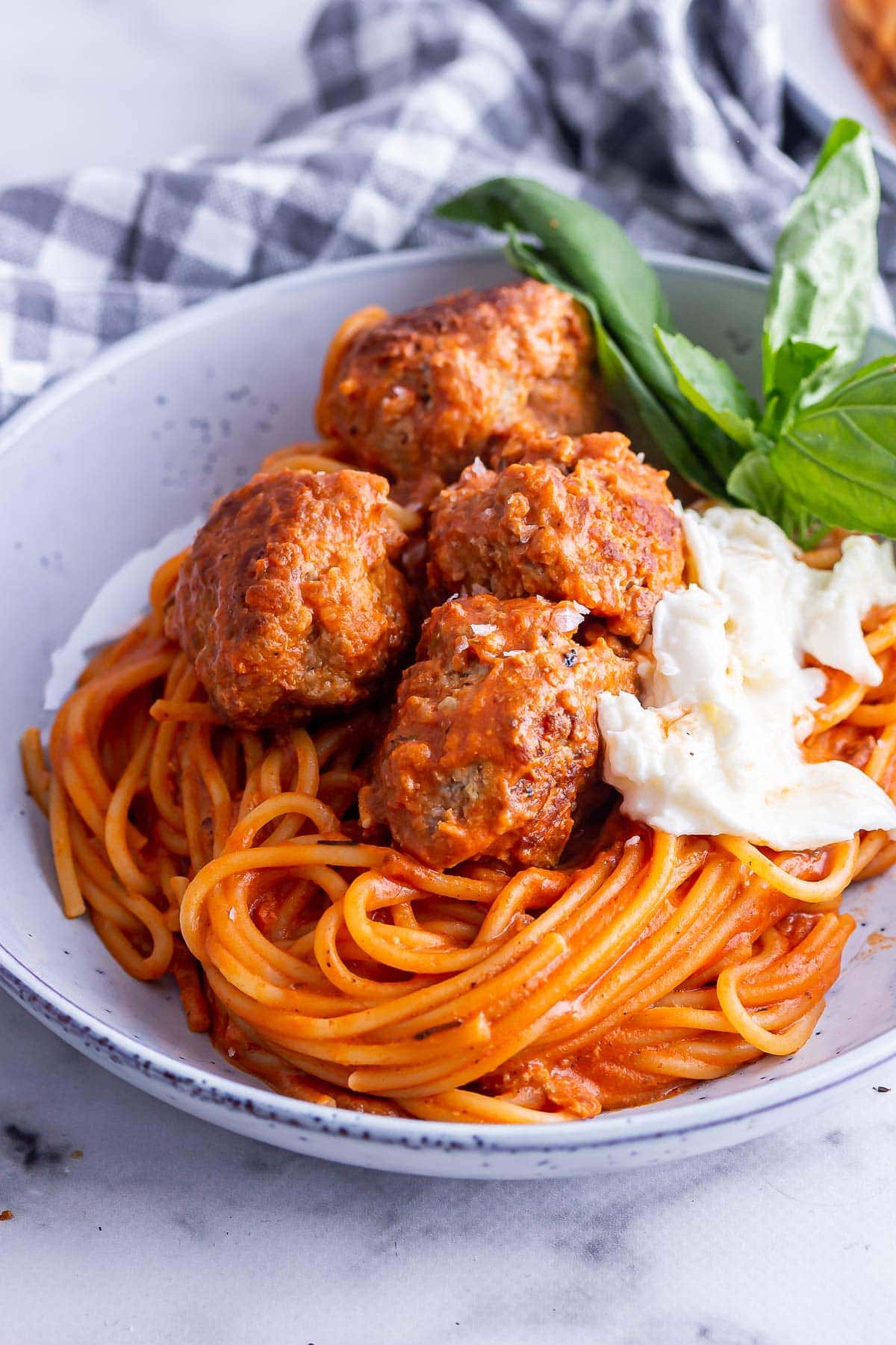 Close up of meatballs and spaghetti with mozzarella and basil