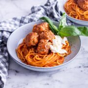 Grey bowl of turkey meatballs and spaghetti on a marble surface