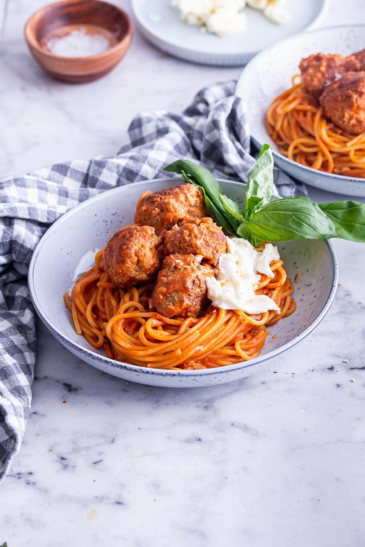 Grey bowl of turkey meatballs and spaghetti on a marble surface