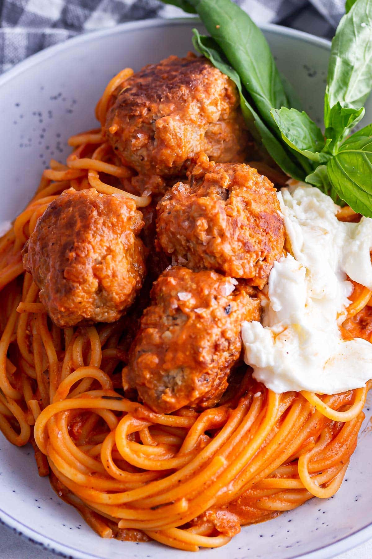 Close up of meatballs on tomato spaghetti with mozzarella