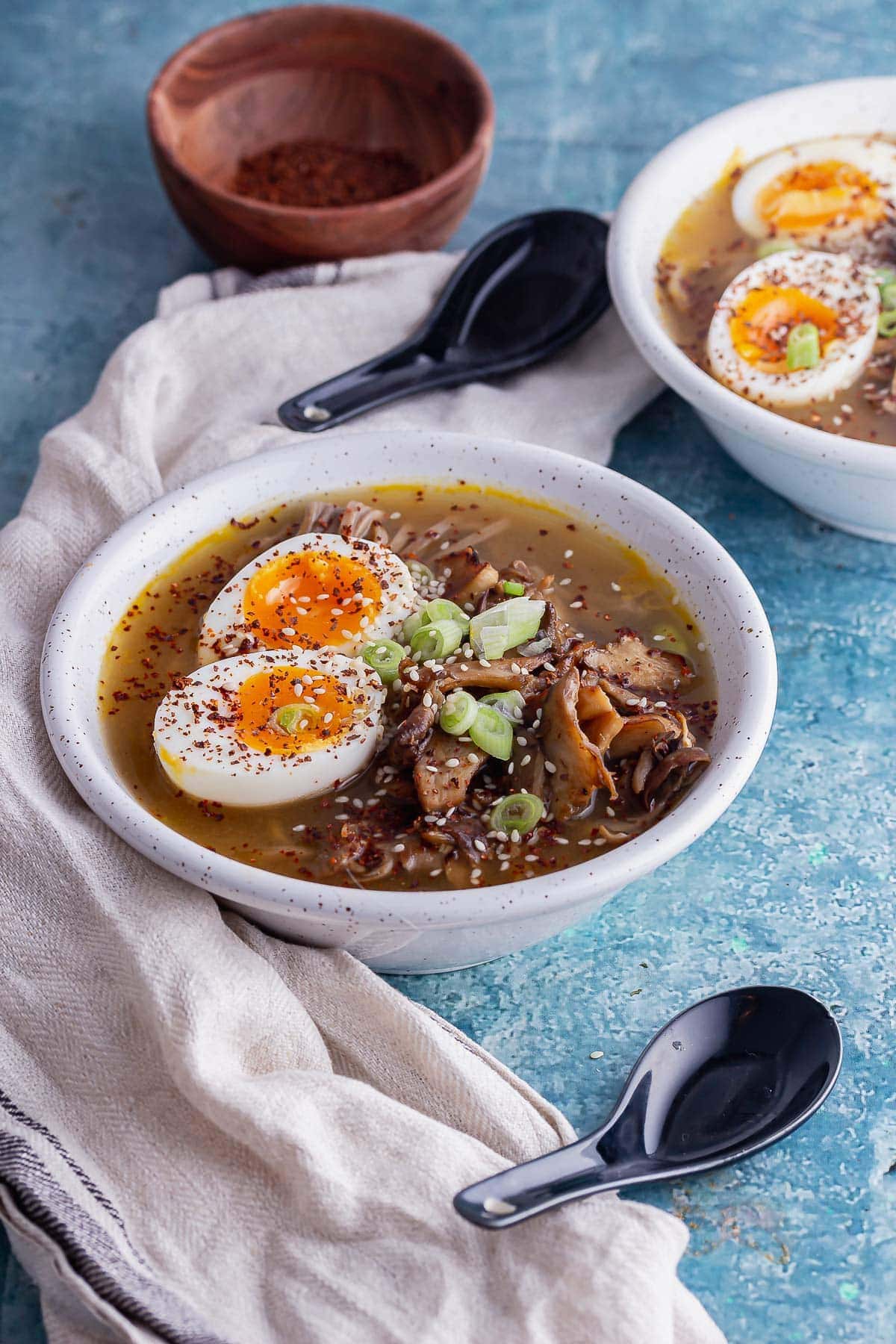 White bowls of mushroom noodle soup with boiled eggs