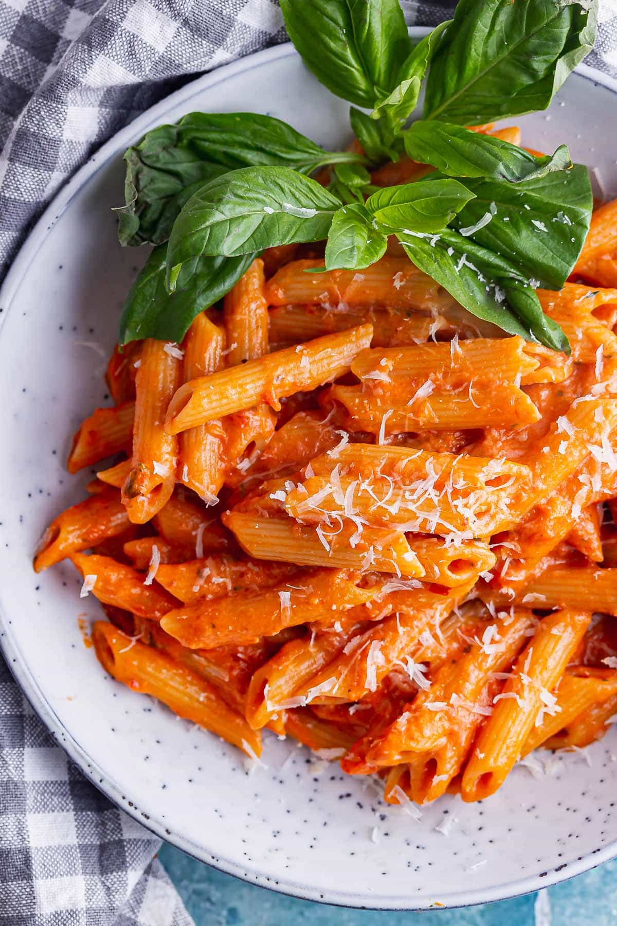 Close up of vodka cream sauce pasta with basil in a blue bowl