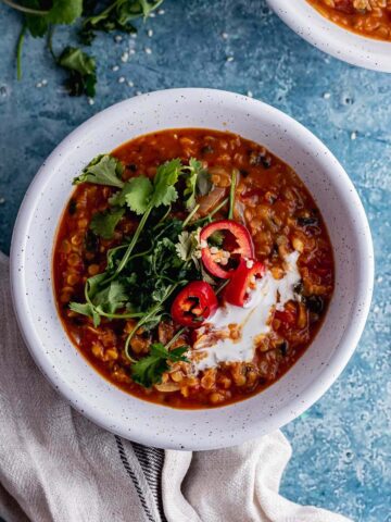 Overhead shot of red lentil soup on a blue background