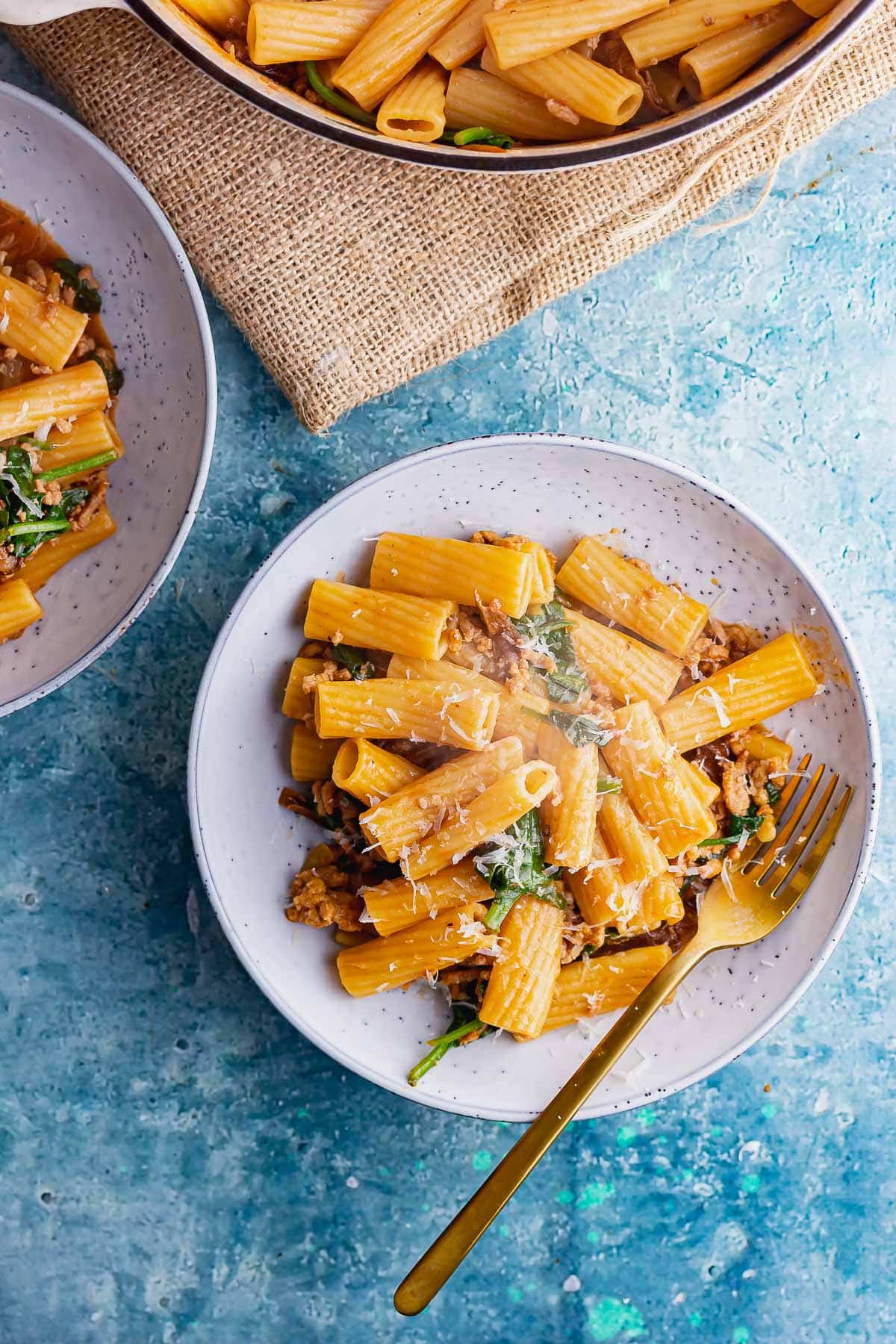 Overhead shot of pork pasta in a blue bowl on a blue surface