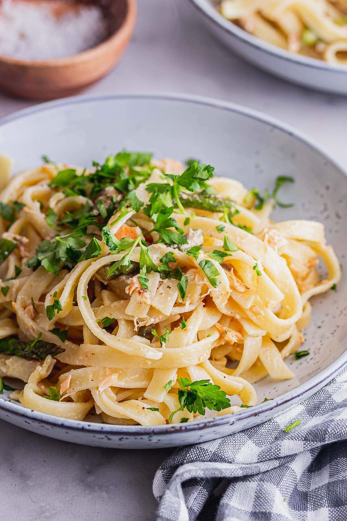 Blue bowl of smoky salmon pasta with a checked cloth