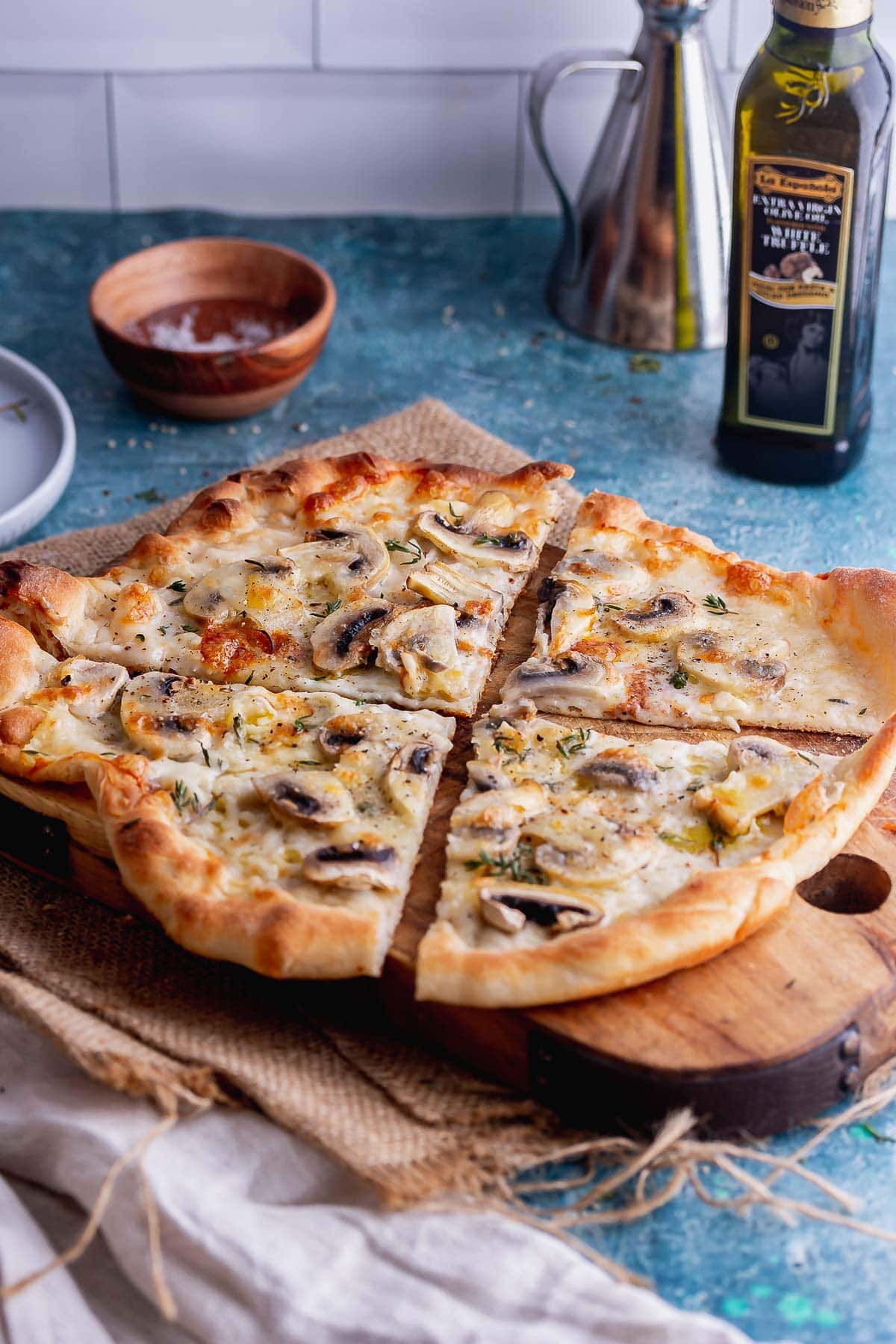 Skillet pizza on a wooden board with a beige cloth