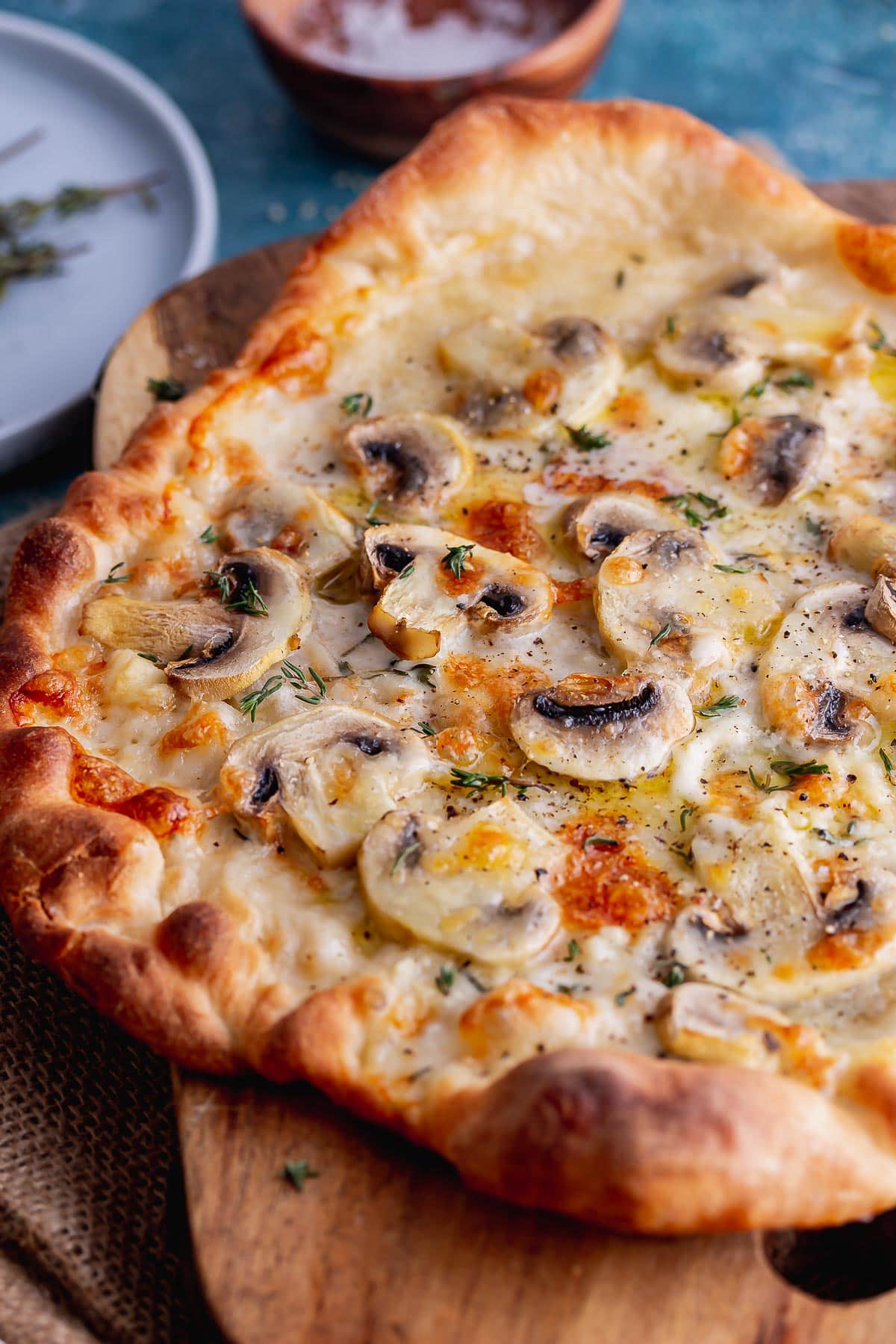 Close up shot of truffle pizza with mushrooms and cheese on a wooden board