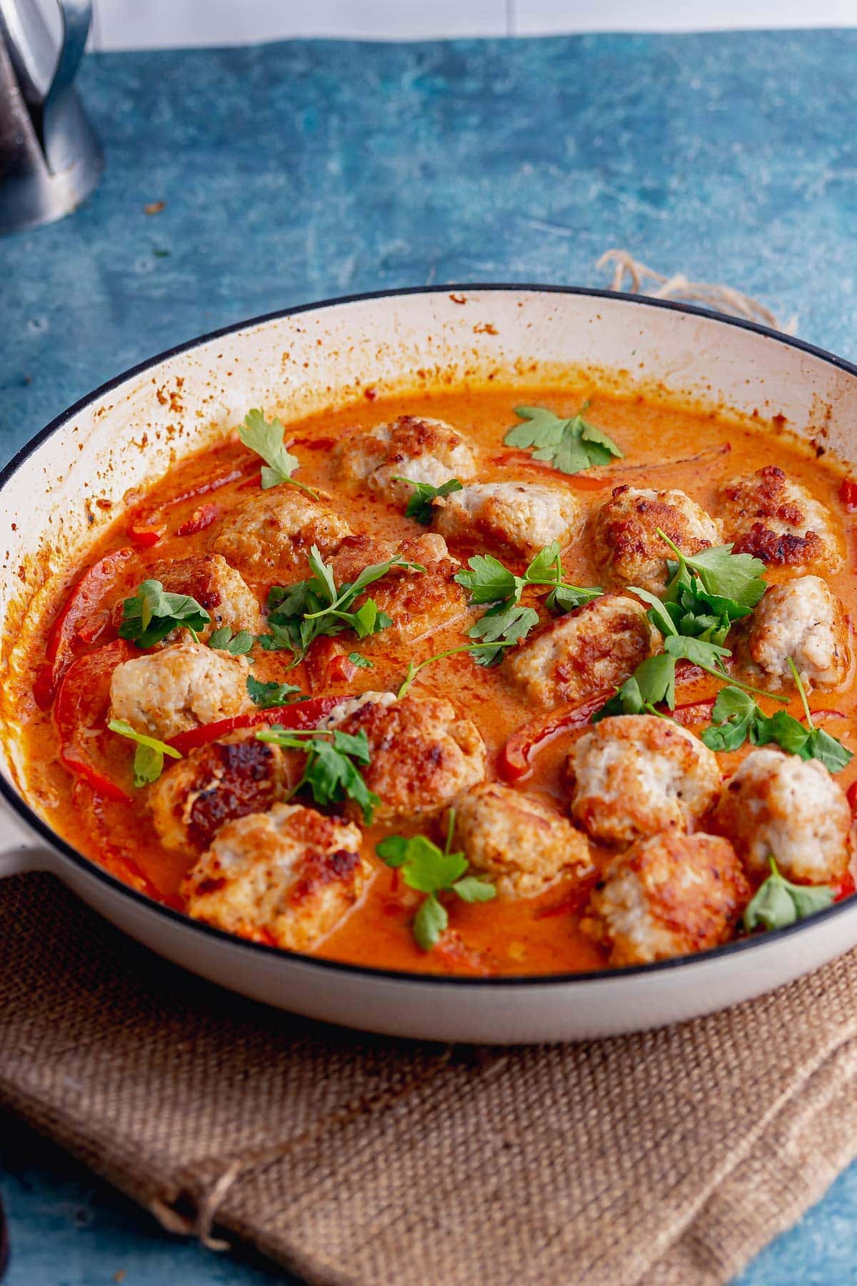 White dish of meatball curry on a hessian mat