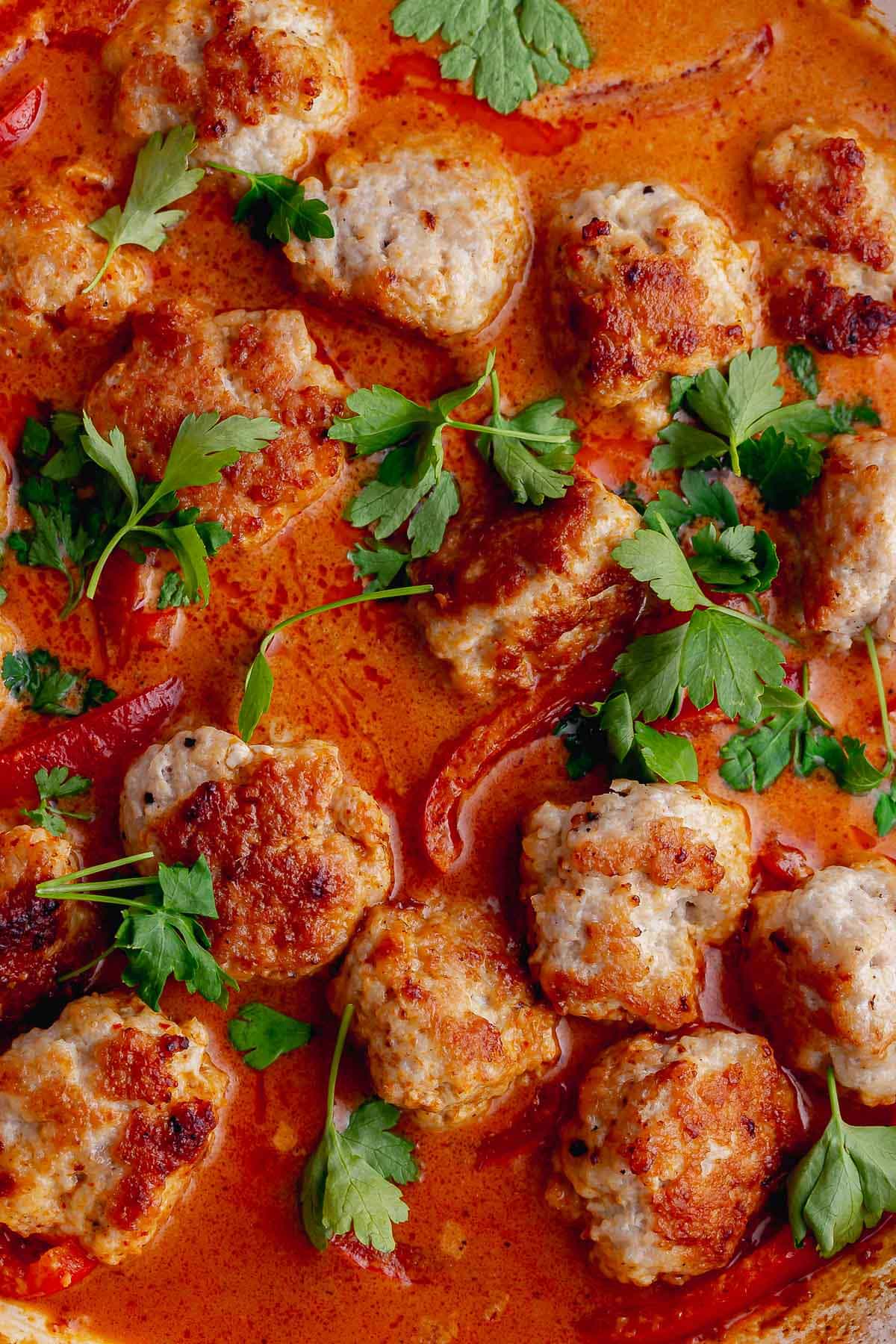 Close up of turkey meatballs in Thai red curry sauce with coriander