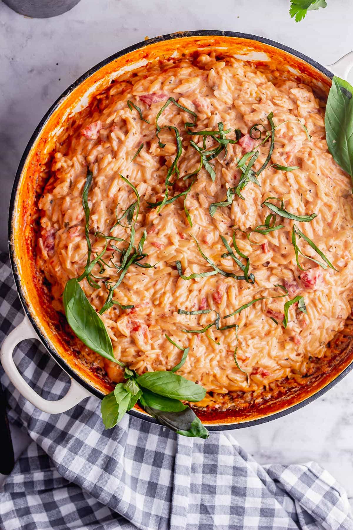 Overhead shot of orzo risotto with basil on a marble background