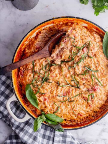 Overhead shot of tomato and mascarpone orzo with a wooden spoon