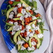 Overhead shot of butternut squash salad with avocado on a marble background