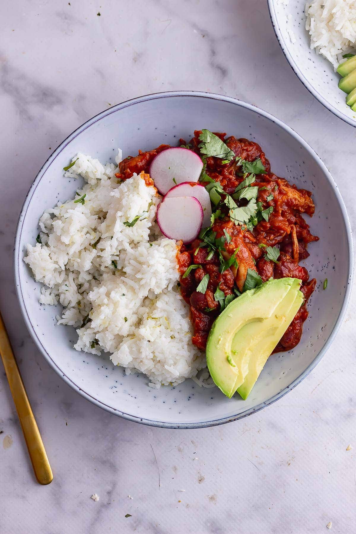 Overhead shot of chicken chilli with avocado and rice